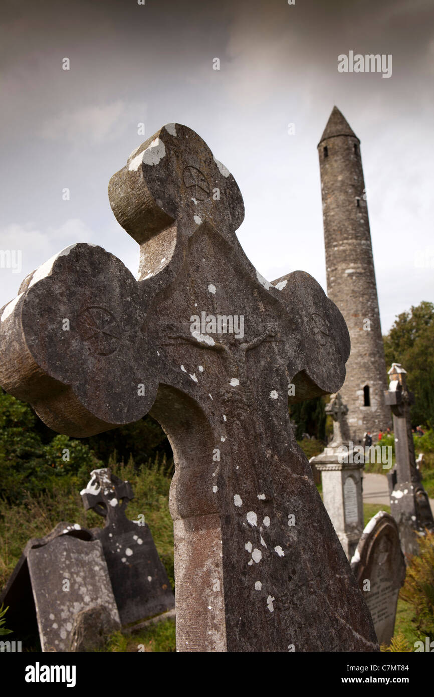 L'Irlande, Co Wicklow, Glendalough, site monastique historique, d'une pierre tombale montrant la crucifixion et la tour ronde Banque D'Images