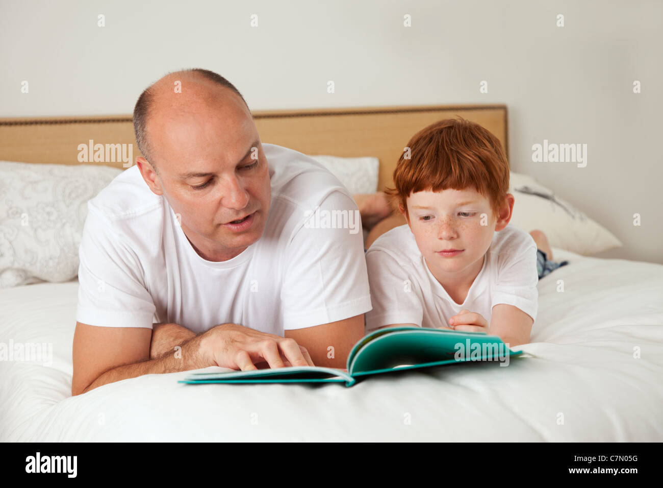 Père et fils lire au lit Banque D'Images