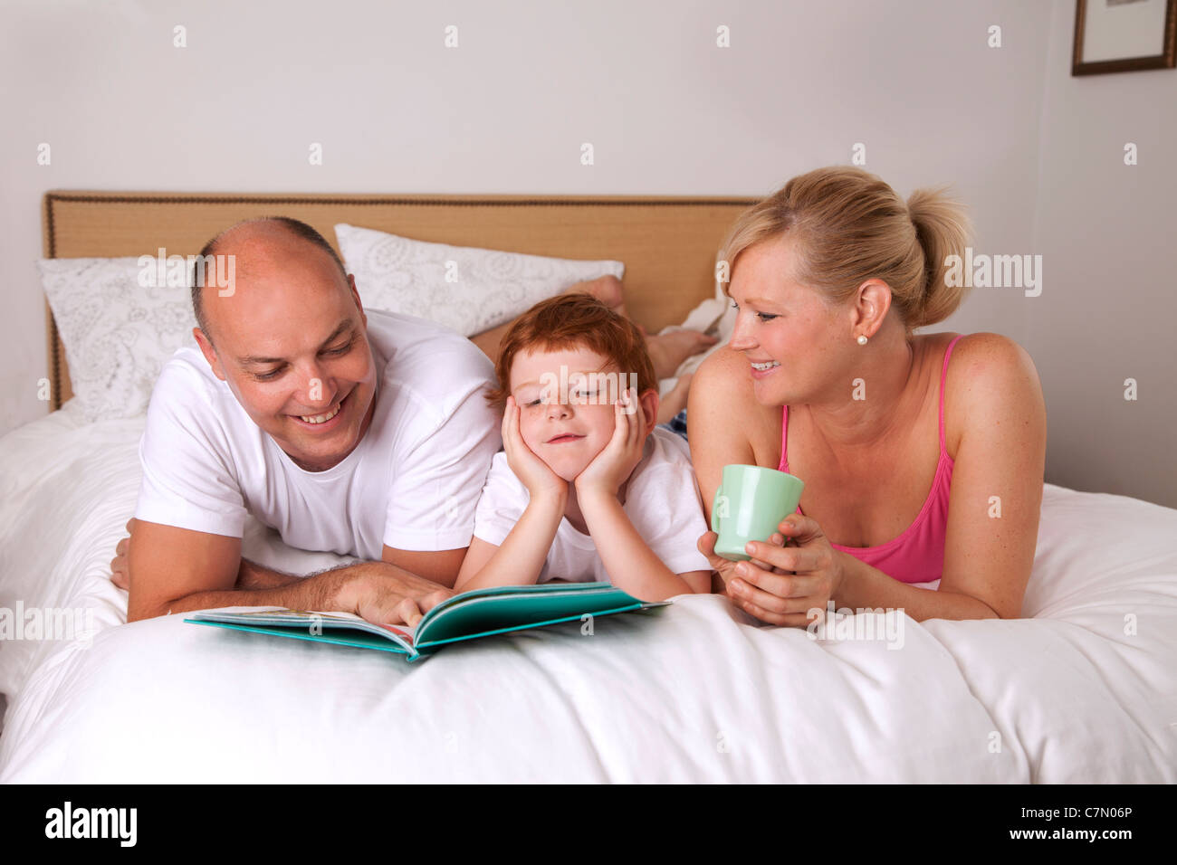 Famille de trois lire au lit ensemble Banque D'Images