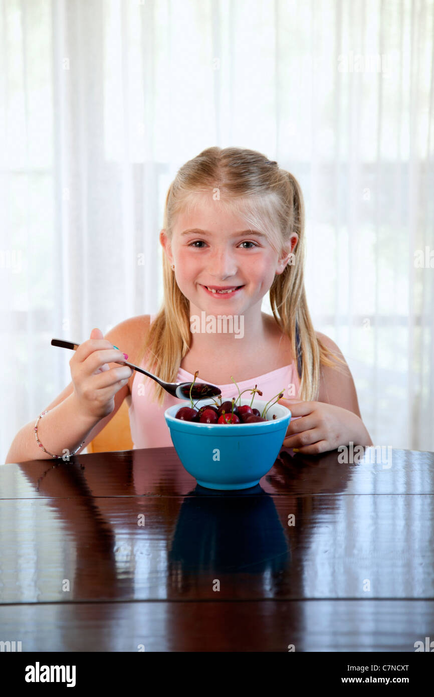 Little girl eating cherries à partir d'un bol Banque D'Images