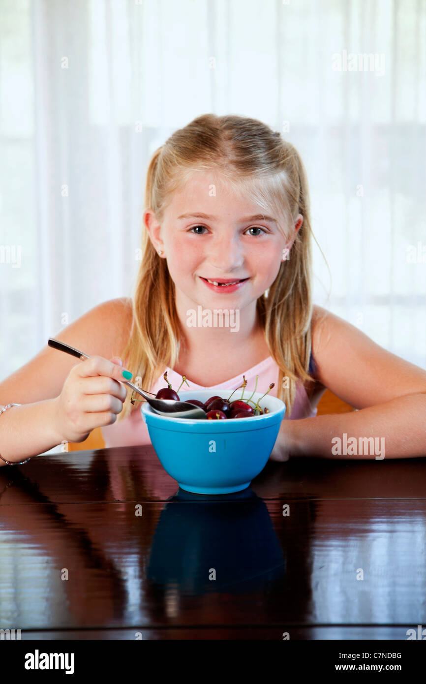 Little girl eating cherries à partir d'un bol Banque D'Images