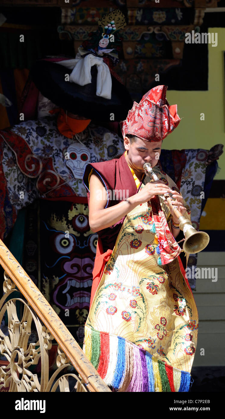 Un moine jouant d'un instrument à vent entraîne les danseurs black hat dans la cour de l'Chowkhang gompa pendant le festival de Leh. Banque D'Images