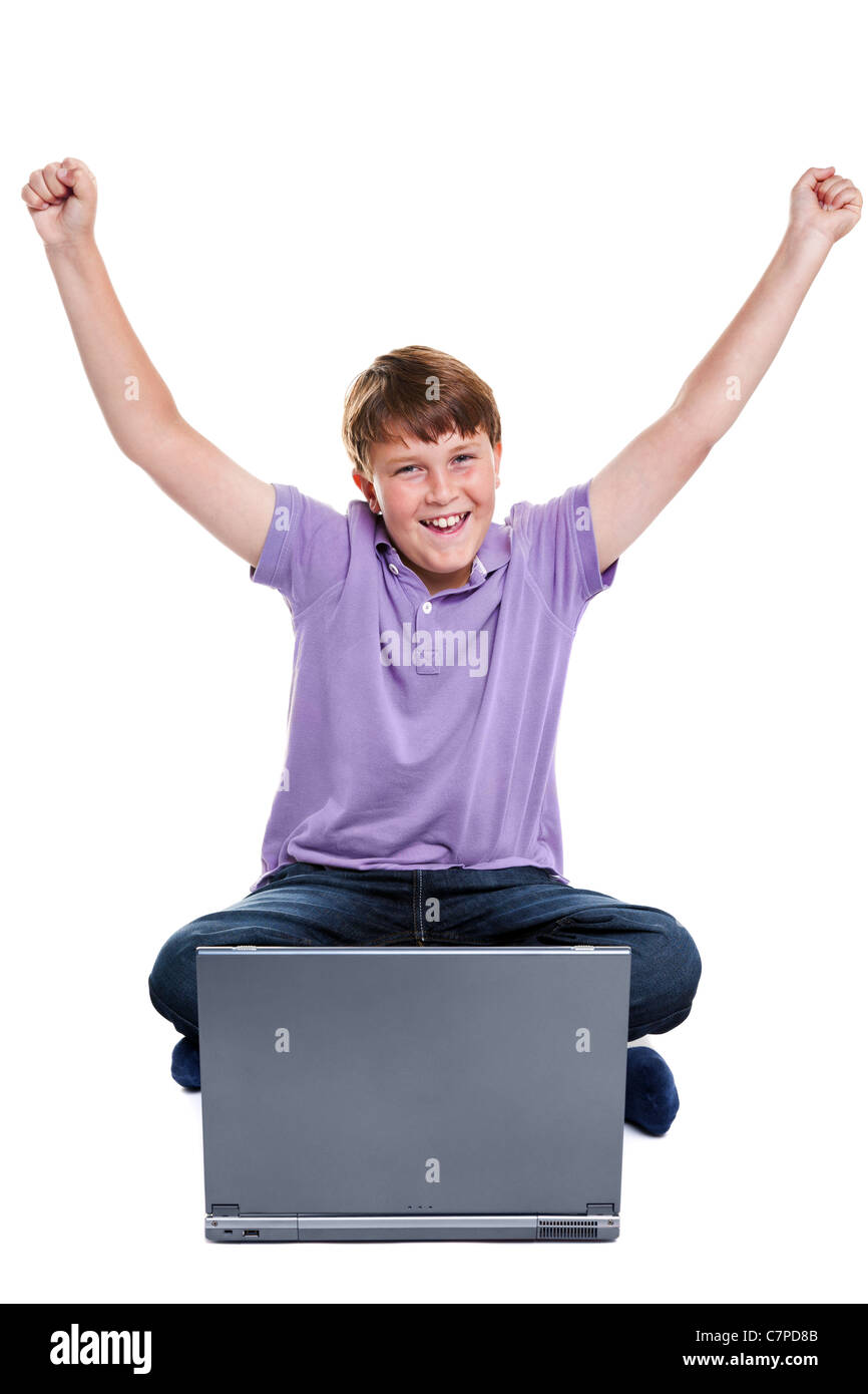 Photo d'un garçon de 11 ans est assise avec un ordinateur portable, ses bras levés en l'air, isolé sur un fond blanc. Banque D'Images