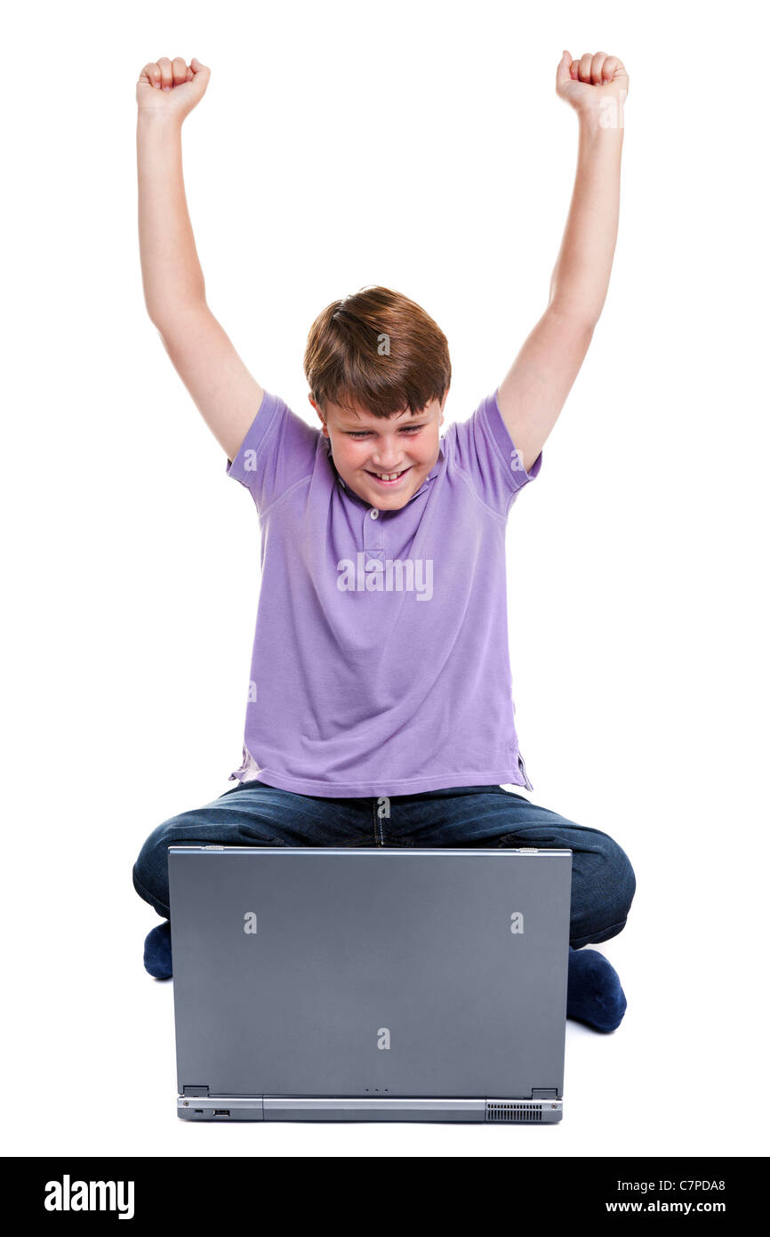 Photo d'un garçon de 11 ans est assise avec un ordinateur portable, ses bras levés en l'air, isolé sur un fond blanc. Banque D'Images