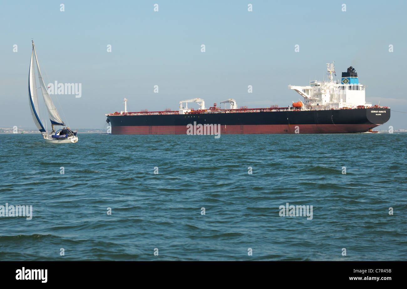 Un superpétrolier transportant du pétrole brut se rapproche de la côte. Un marin se conserve bien à l'écart du léviathan industriel. Banque D'Images