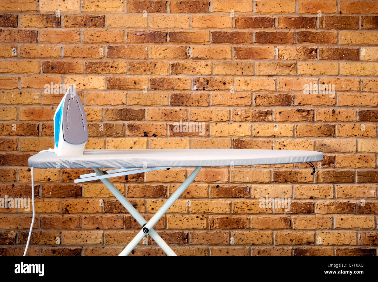 Retro style composition d'une planche à repasser et fer à repasser against brick wall Banque D'Images