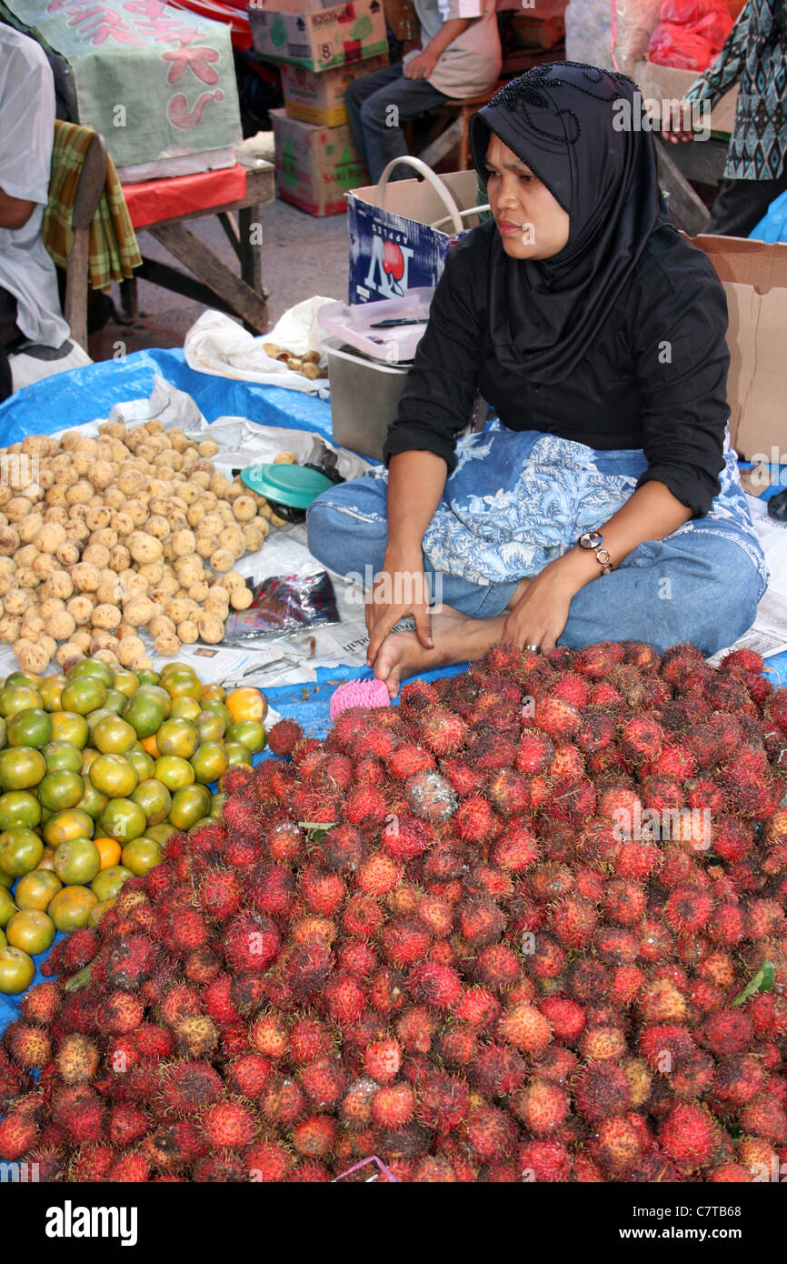 Vente Dame indonésien et ramboutan oranges sur son échoppe de marché Banque D'Images