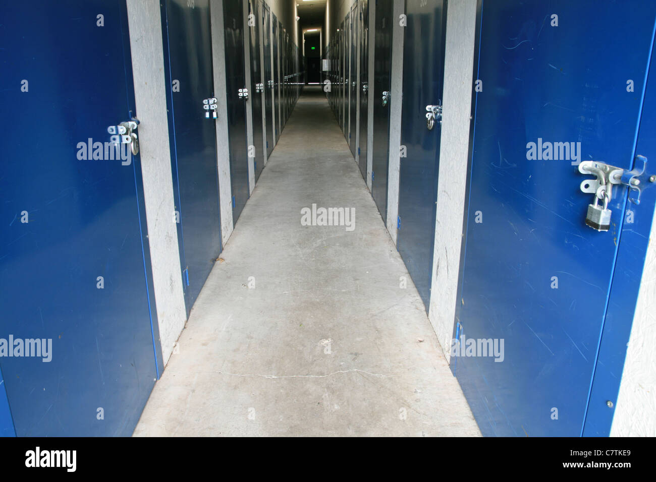 Vue horizontale dans un couloir dans un bâtiment de stockage autonome avec cadenassé portes bleues de chaque côté Banque D'Images