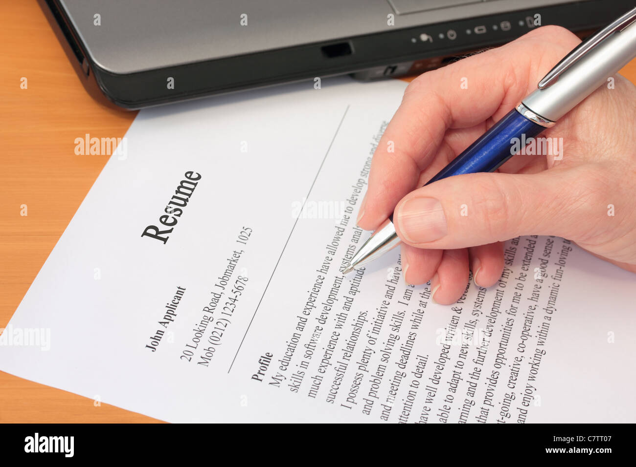 La main avec un stylo Correction cv par ordinateur portable Banque D'Images