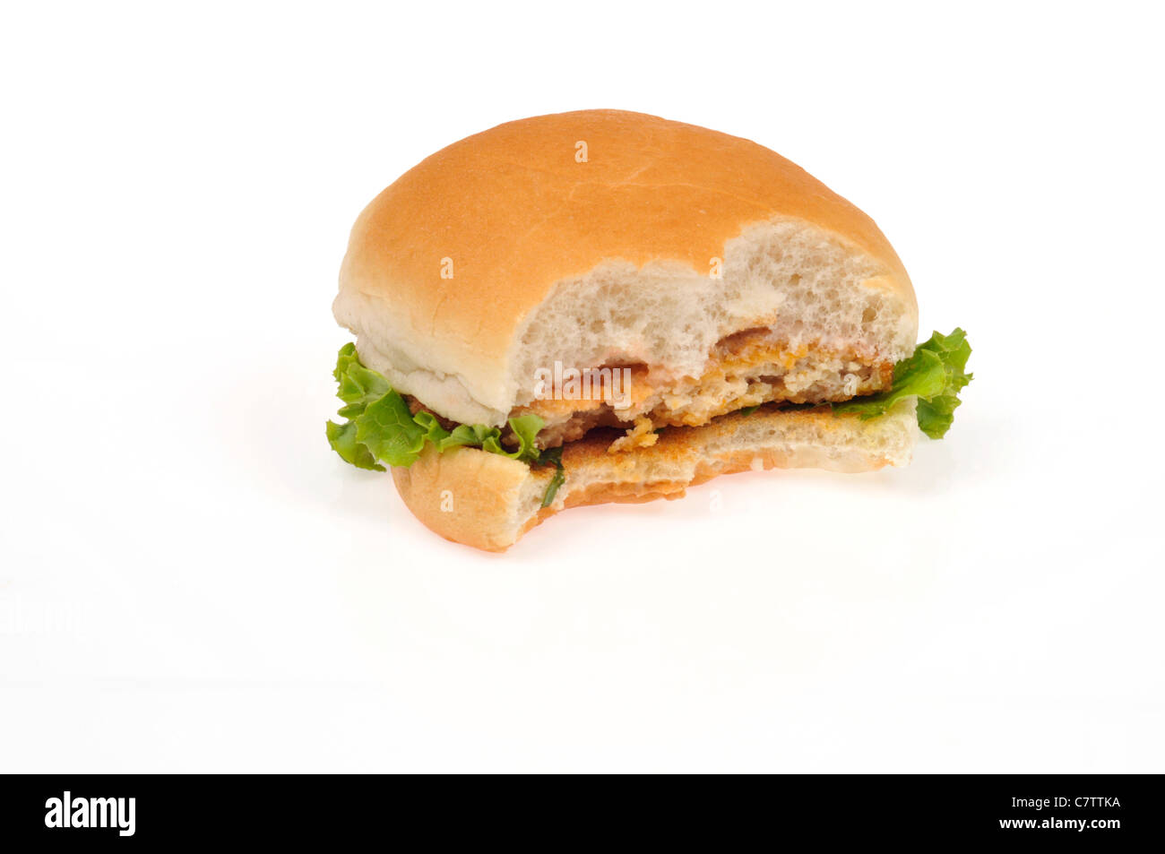 Sandwich au poulet pané patty dans un pain avec de la laitue et un en-cas pris hors de lui sur fond blanc, découpe. Banque D'Images