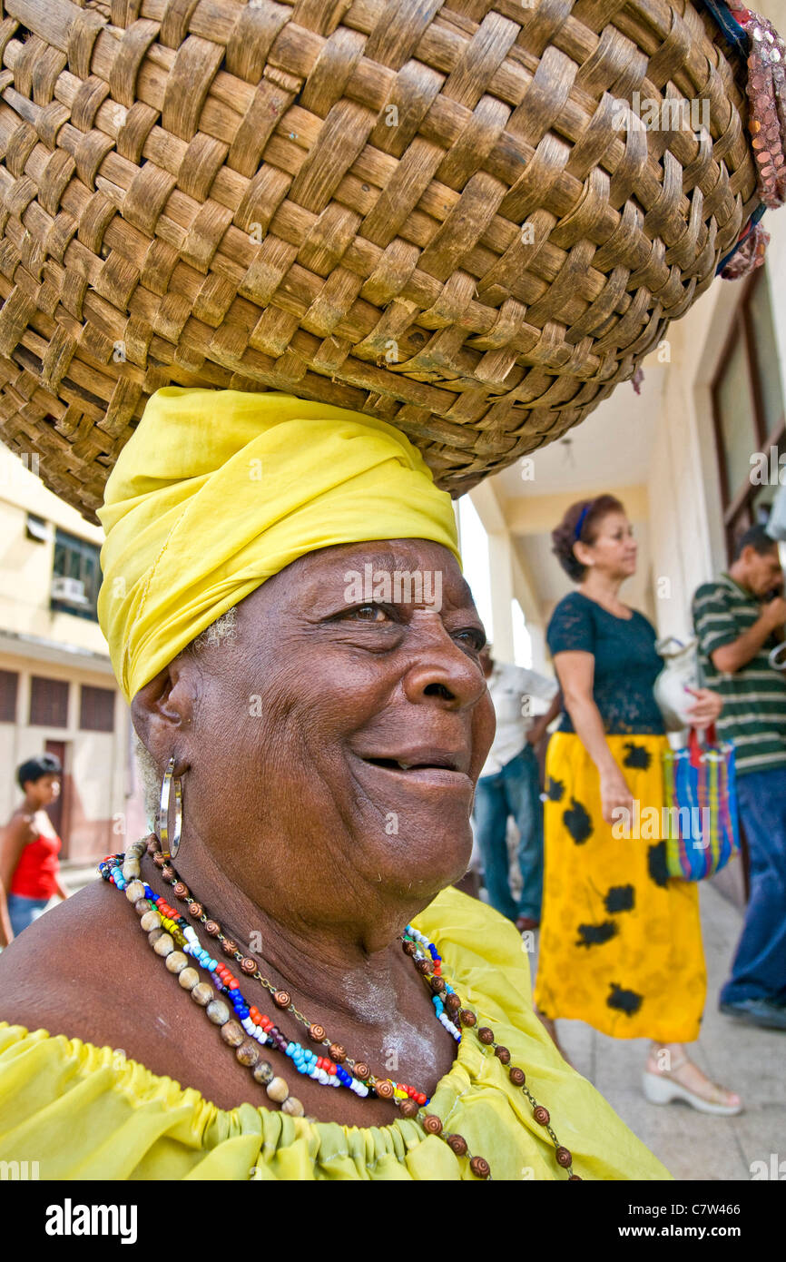 Cuba, Santiago, senior woman carrying basket on head Banque D'Images