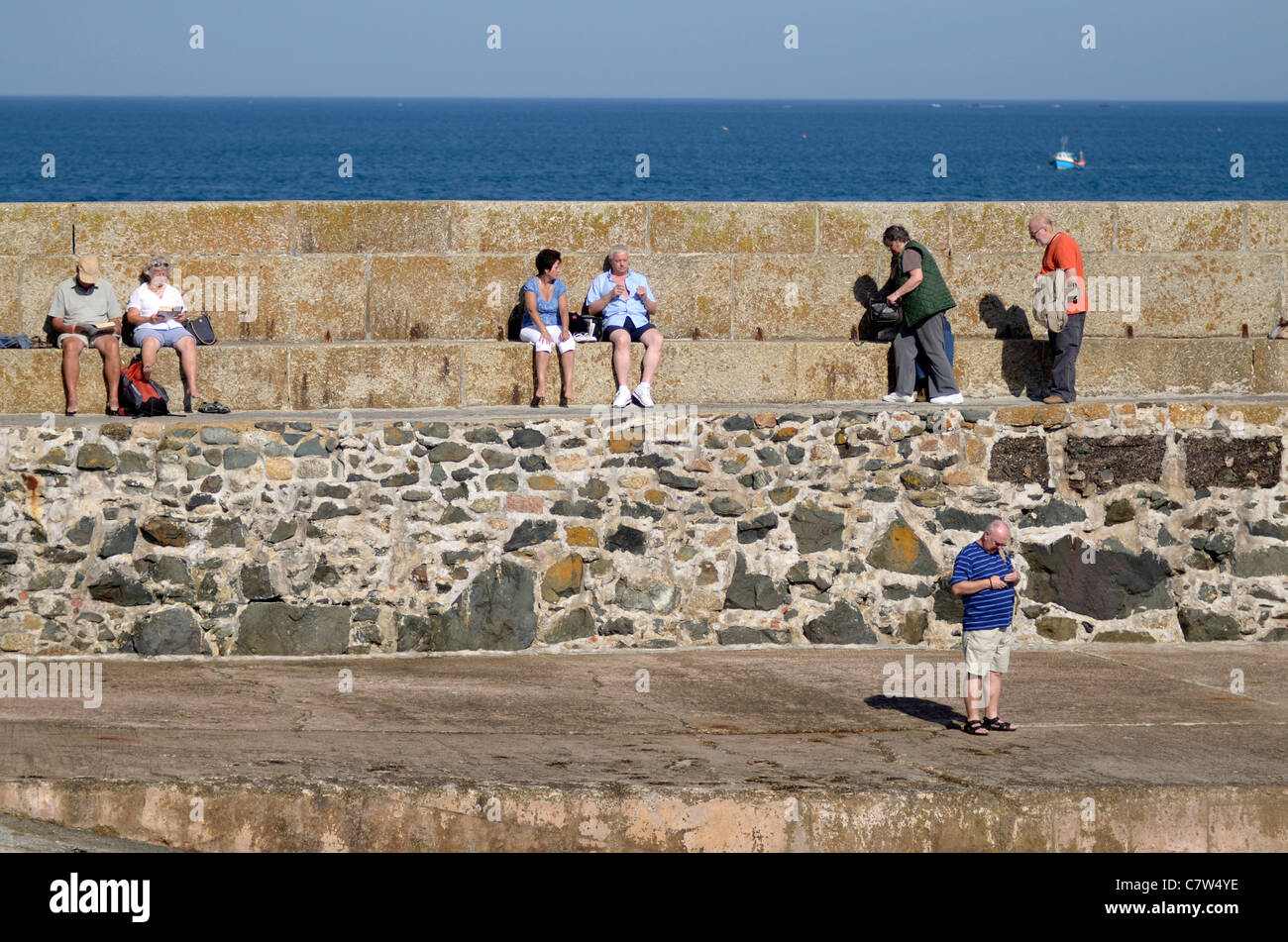 Les touristes assis sur le mur du port St Ives Cornwall UK Banque D'Images