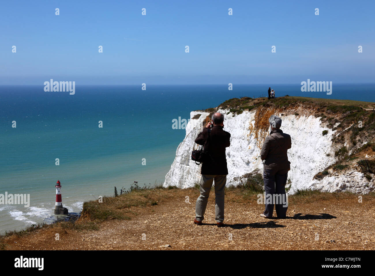 Touristes regardant la vue à Beachy Head, phare en arrière-plan , près d'Eastbourne , East Sussex , Angleterre Banque D'Images