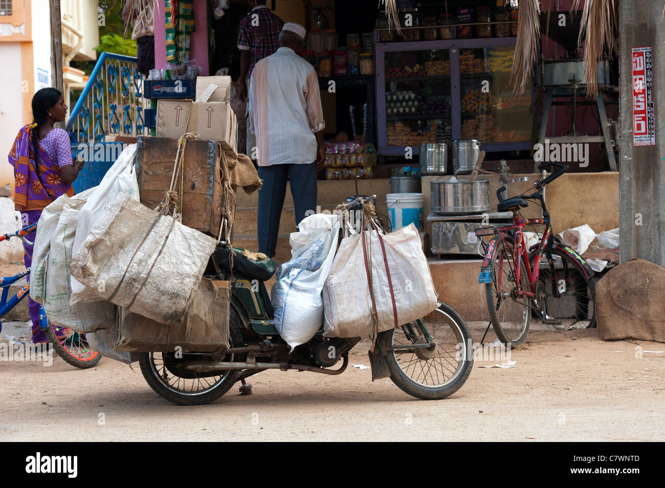 Cyclomoteur ladened indiennes avec des marchandises à vendre à des magasins locaux dans les rues de Puttaparthi, Andhra Pradesh, Inde Banque D'Images