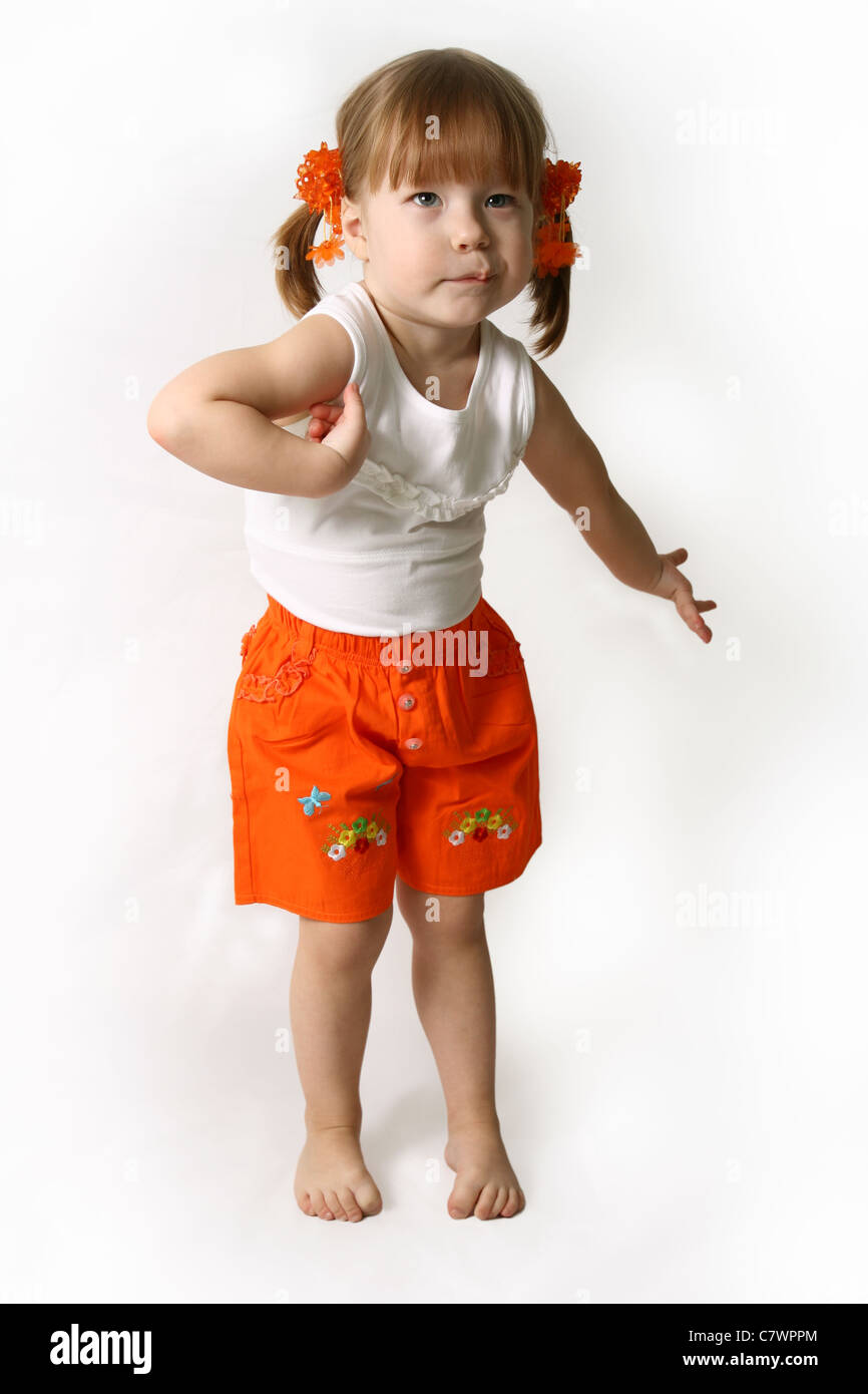 Petite fille dans un short orange se tortille et pose le contexte