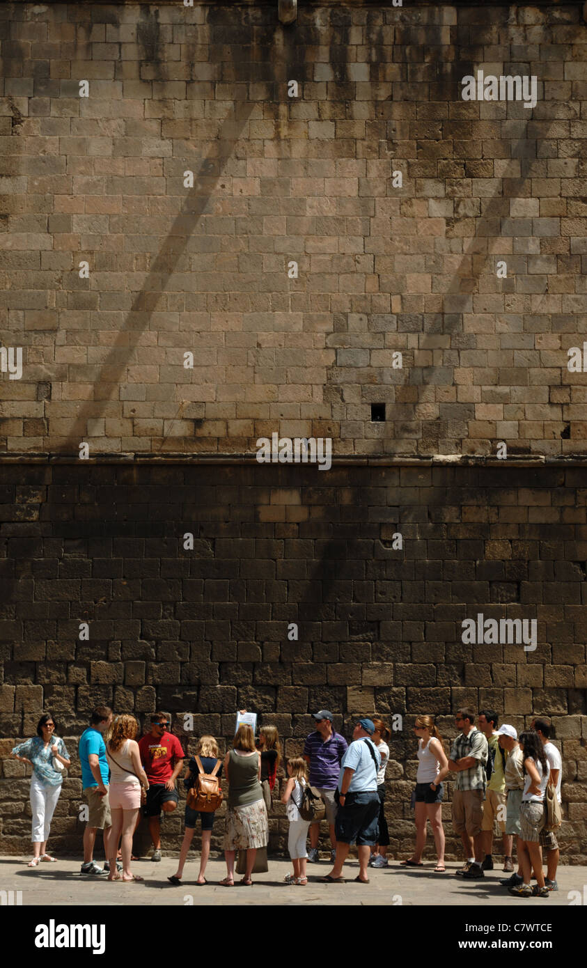 Les touristes : une visite à pied de groupe par un vieux mur romain touristique dans la région de Plaza del Reys, Barcelone, Catalogne (Espagne). Banque D'Images