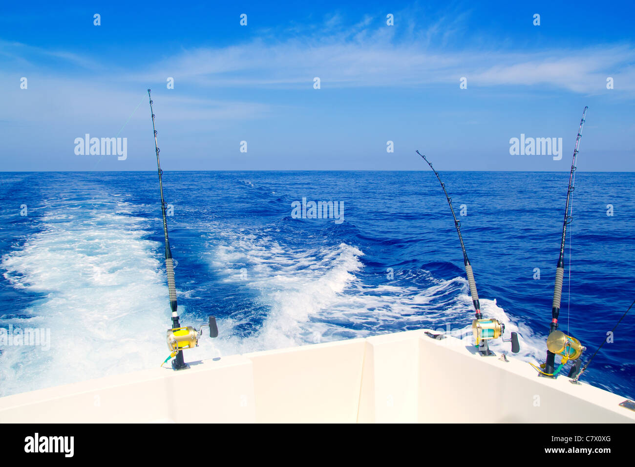 Bateau de pêche à la traîne dans la mer d'un bleu profond avec des cannes et moulinets Banque D'Images