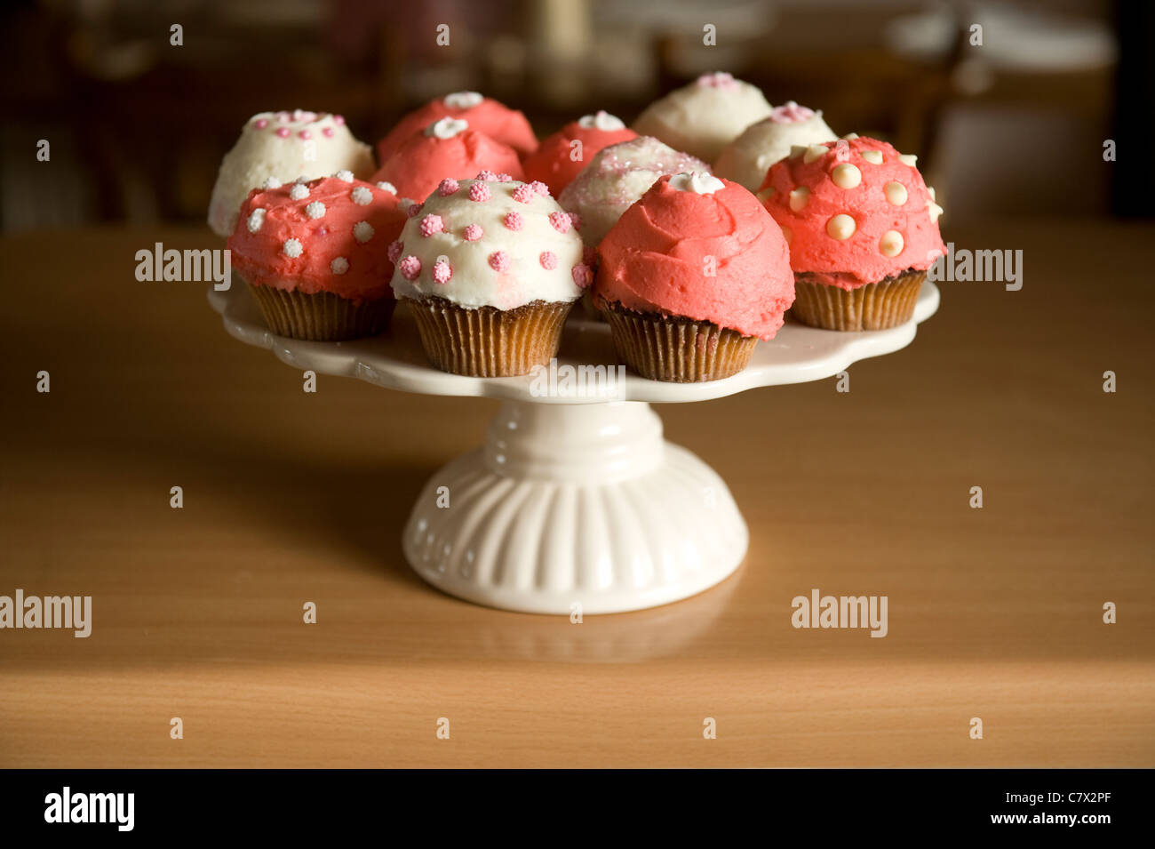 Cupcakes rose et blanc givré diverses conceptions sur la plaque à gâteau et rétroéclairé comptoir Banque D'Images