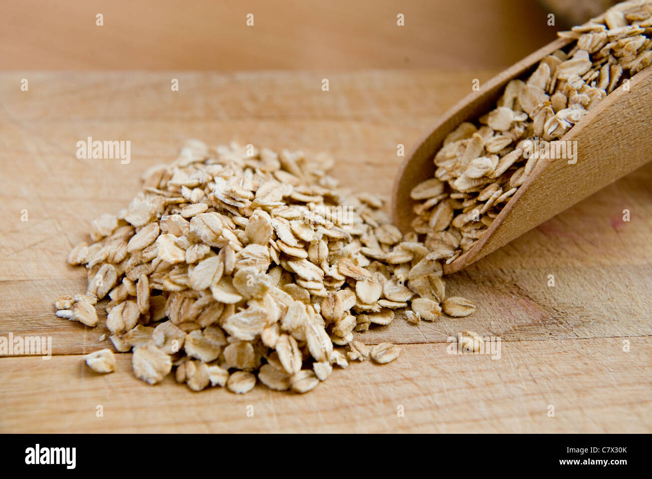 L'avoine se répandre à partir d'une pelle en bois sur une planchette de bois close up Banque D'Images