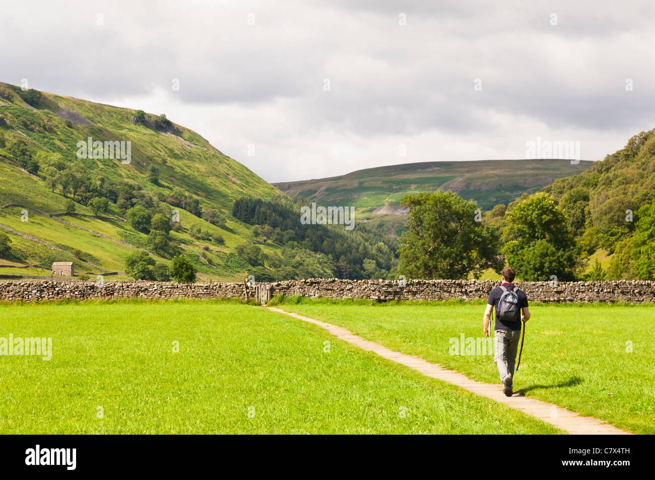 Un homme marche à Muker dans Swaledale dans Yorkshire du Nord , Angleterre , Angleterre , Royaume-Uni Banque D'Images