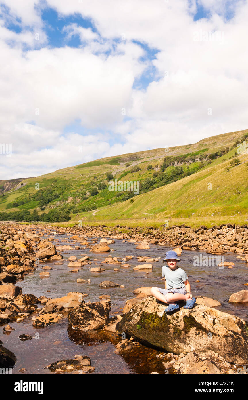 Un garçon de sept ans à la rivière Swale à Muker dans Swaledale dans Yorkshire du Nord , Angleterre , Angleterre , Royaume-Uni Banque D'Images