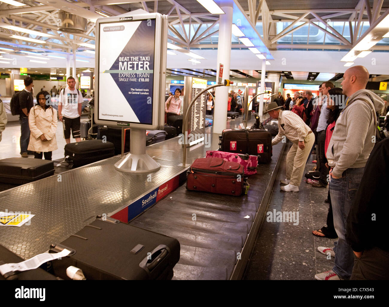 Les passagers de l'air la collecte de vos bagages dans la salle des bagages, terminal 3 de l'aéroport Heathrow de Londres, UK Banque D'Images