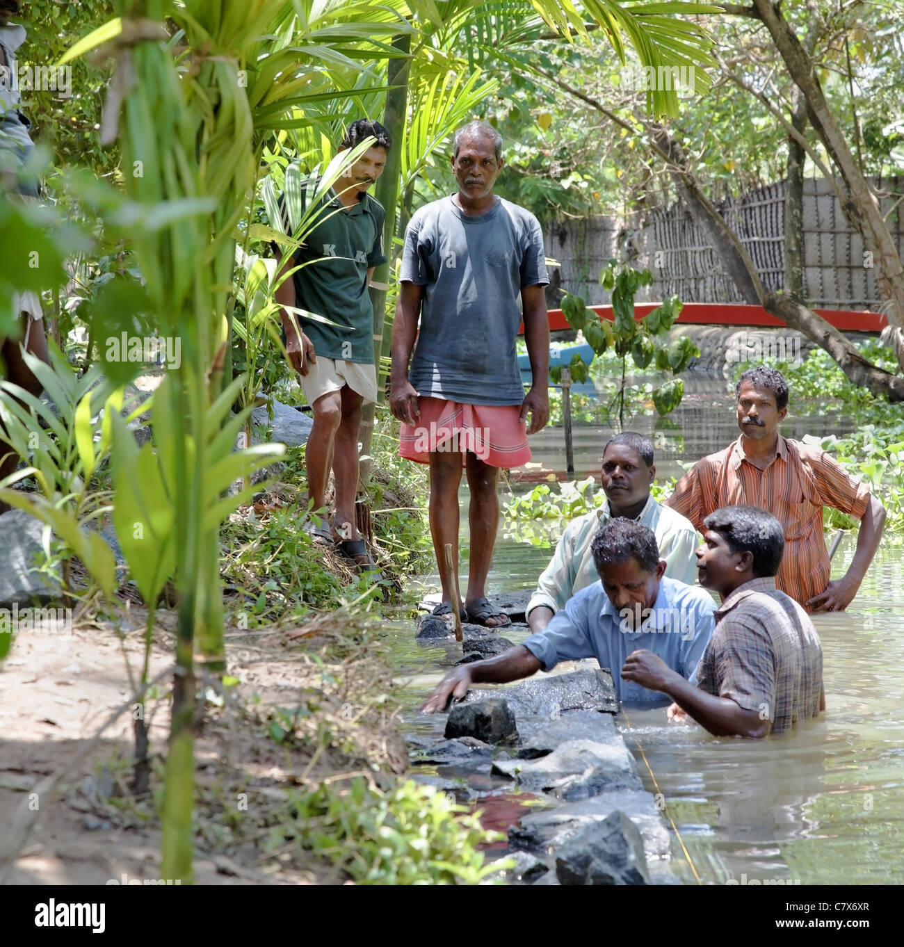 Format carré de constructeurs Construction piste travaille sur un mur en pierre sèche sous l'eau dans le Kerala en Inde, avec l'espace vertical de la récolte Banque D'Images