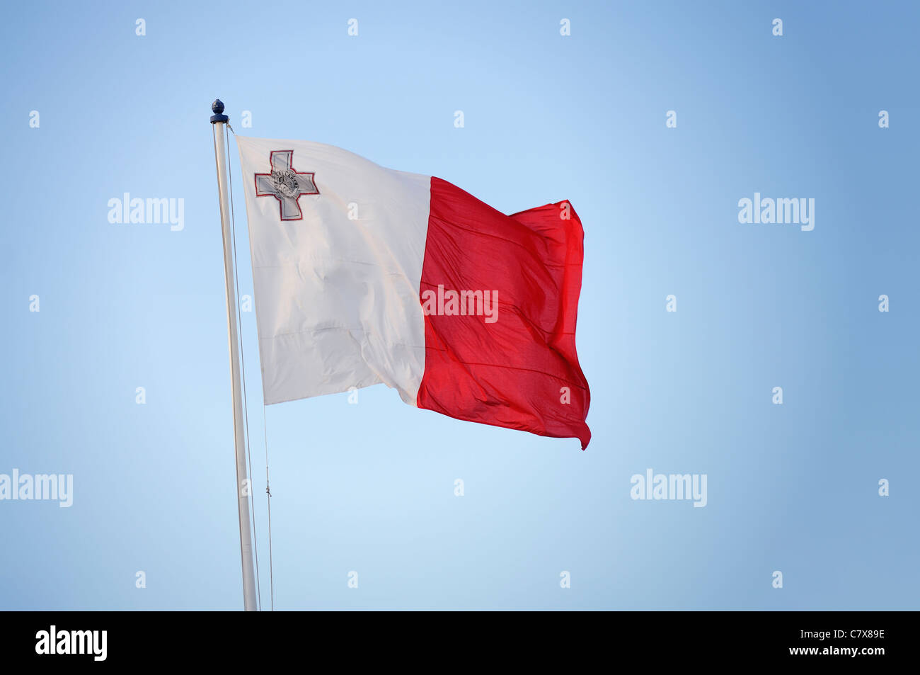 Brandir le drapeau maltais dans le vent. Banque D'Images