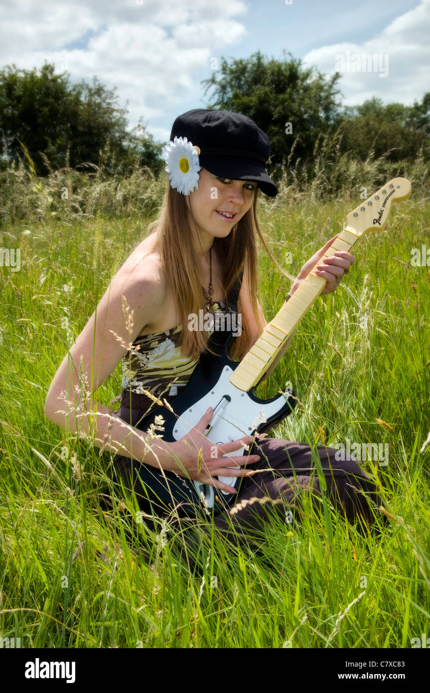 Attractive young woman avec un look hippie chick jouer avec guitare dans le pré à Bristol royaume uni le jour d'été Banque D'Images