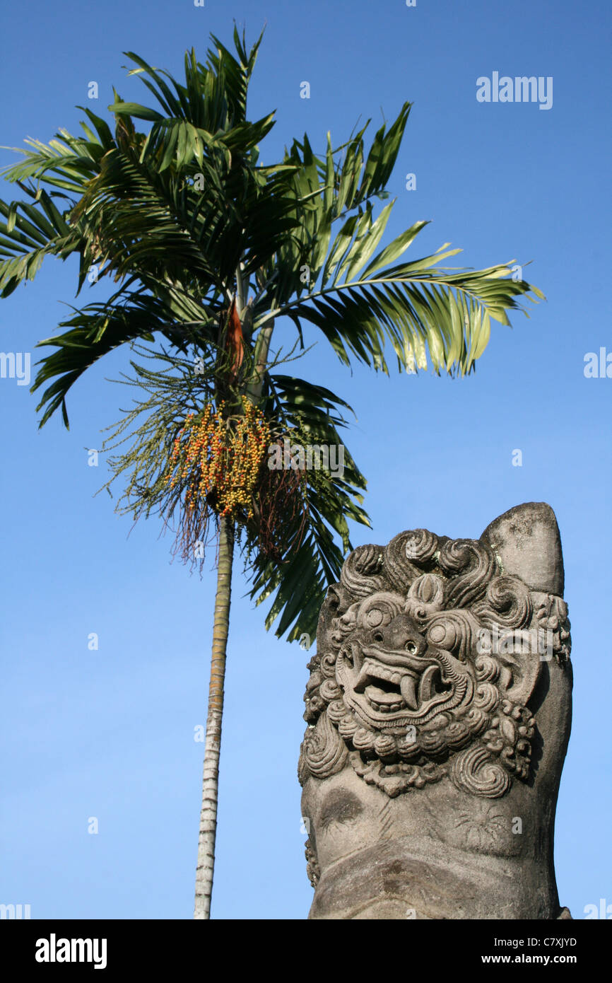 Démon de pierre se trouve à côté de palmier d'Arec Banque D'Images