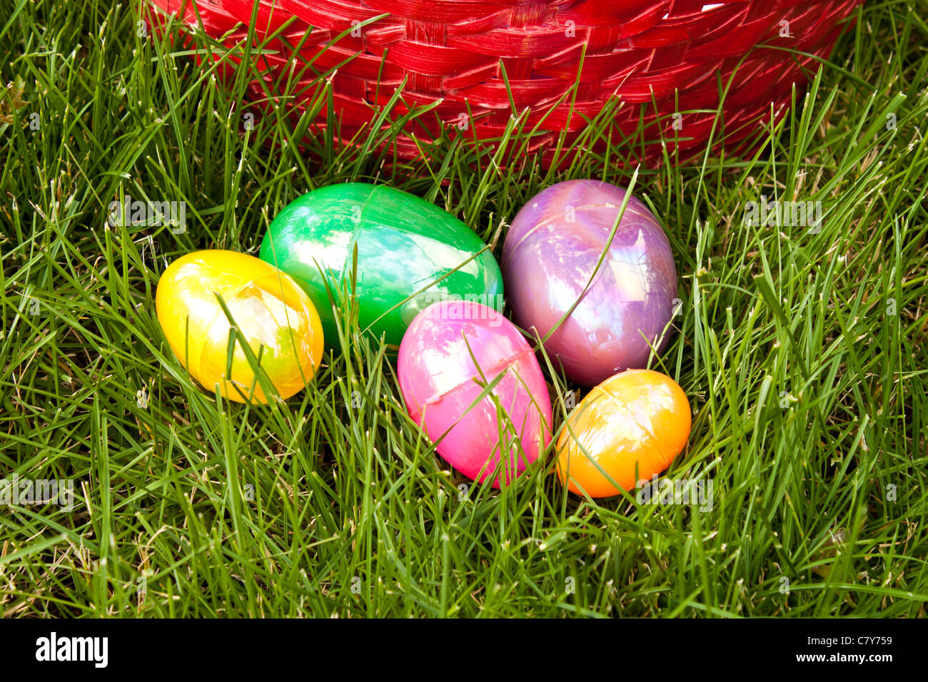 Œufs de Pâques colorés dans l'herbe en face du panier Banque D'Images