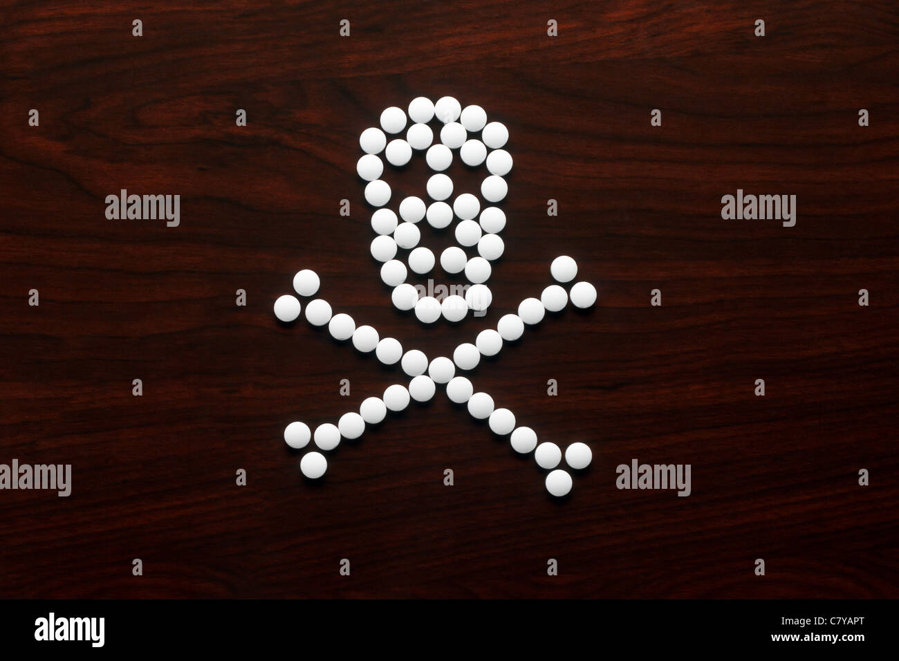 Pilules blanches formées dans un crâne sur la surface en bois Banque D'Images