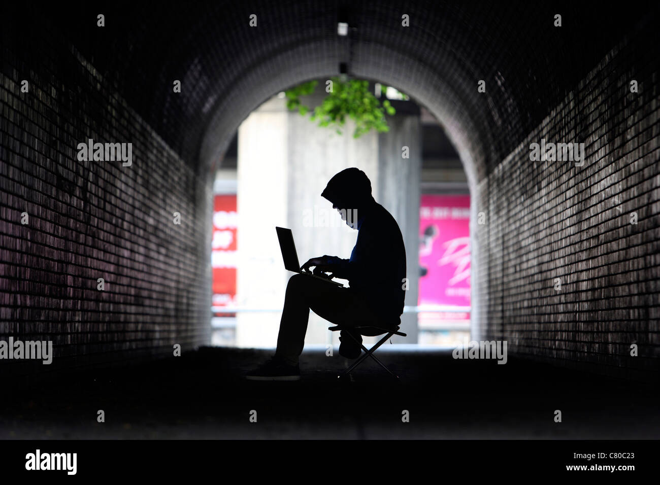 En informatique, hacker, siège de conspirateur, dans un tunnel, avec un ordinateur portable. Photo symbole, de la criminalité sur Internet. Banque D'Images