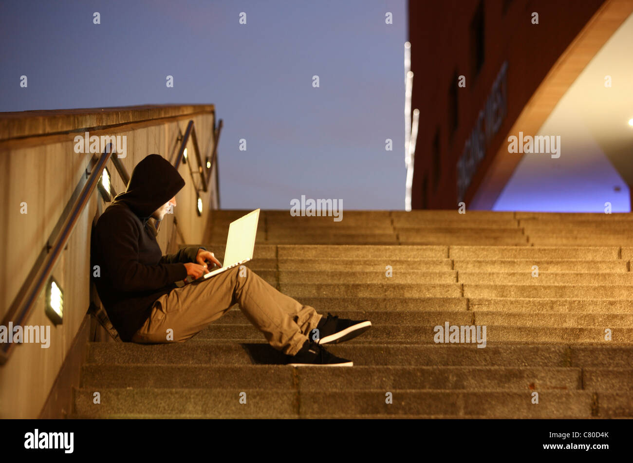 En informatique, hacker, siège de conspirateur, à l'extérieur, sur les escaliers, avec un ordinateur portable. Photo symbole, de la criminalité sur Internet. Banque D'Images