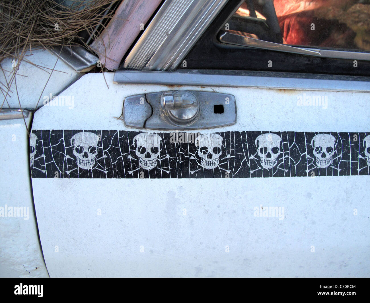 Autocollant crâne fendu sur une vieille voiture abandonnée Banque D'Images