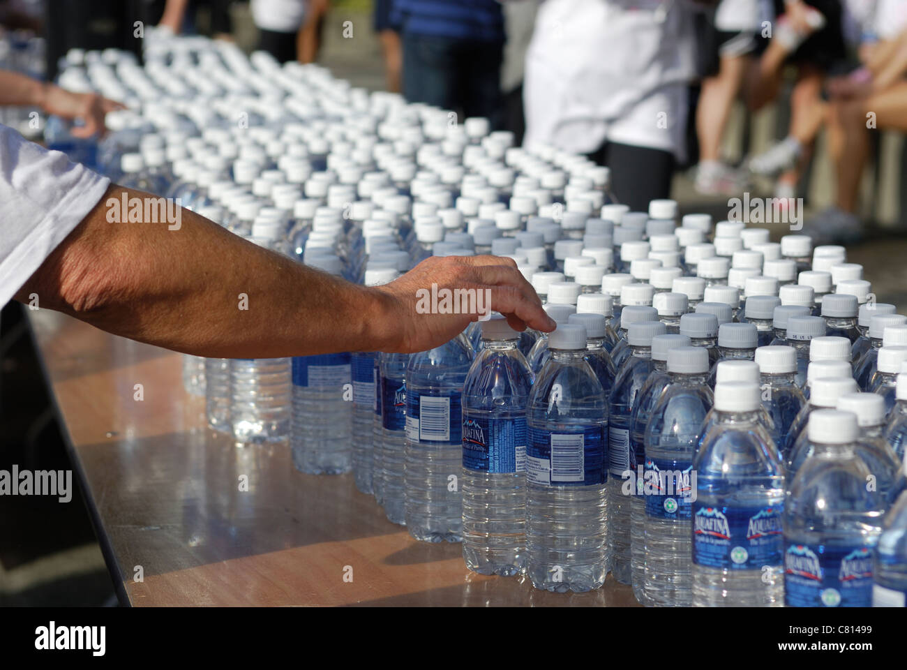 Pour arriver à la main une bouteille d'eau à partir d'une table pleine d'eau en bouteille. Banque D'Images