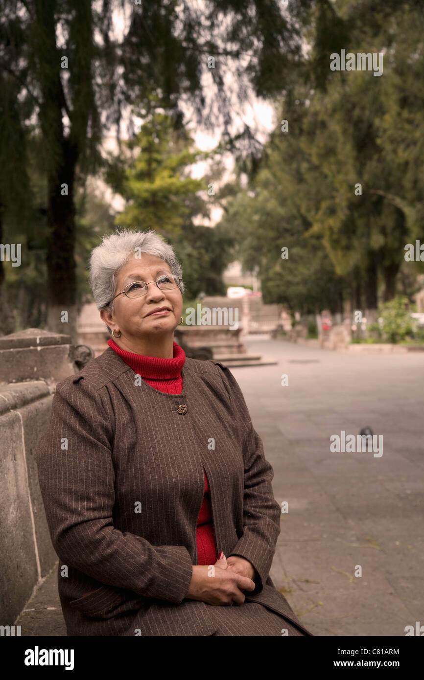 Senior Hispanic woman sitting in park Banque D'Images