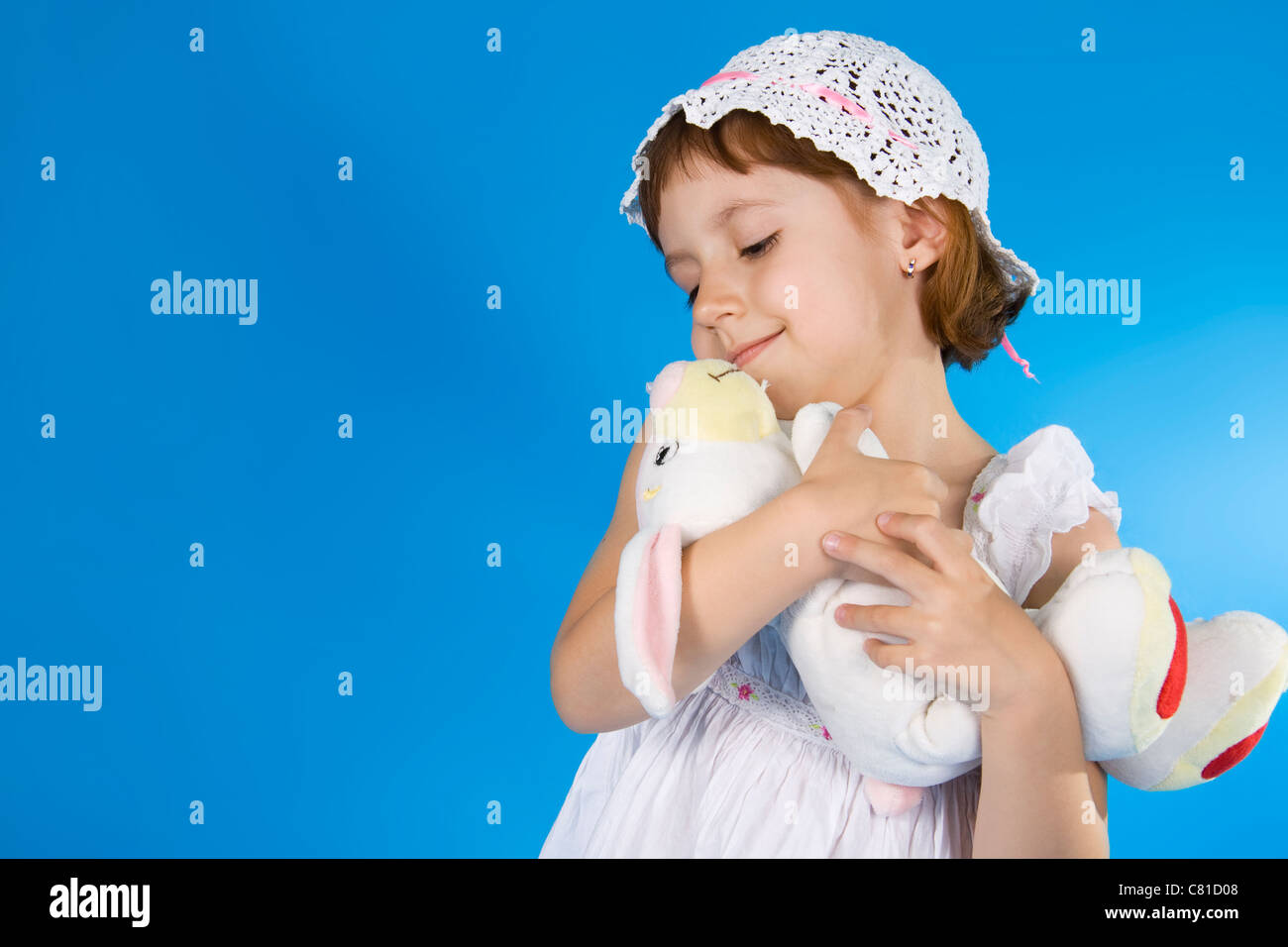 Petite fille joue avec un jouet. Un fond bleu. Banque D'Images