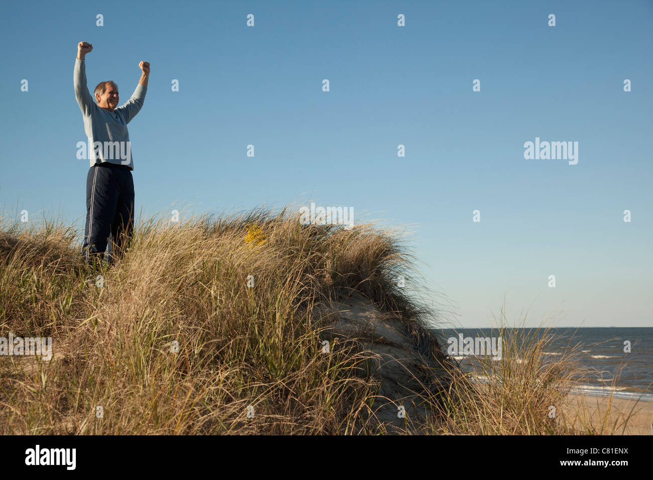 Man cheering on sand dune près de ocean Banque D'Images