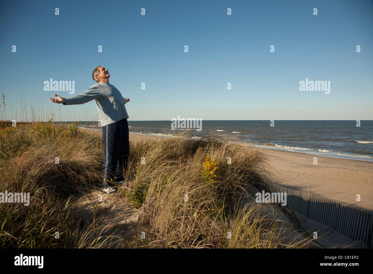 Homme debout sur la dune de sable près de ocean with arms outstretched Banque D'Images