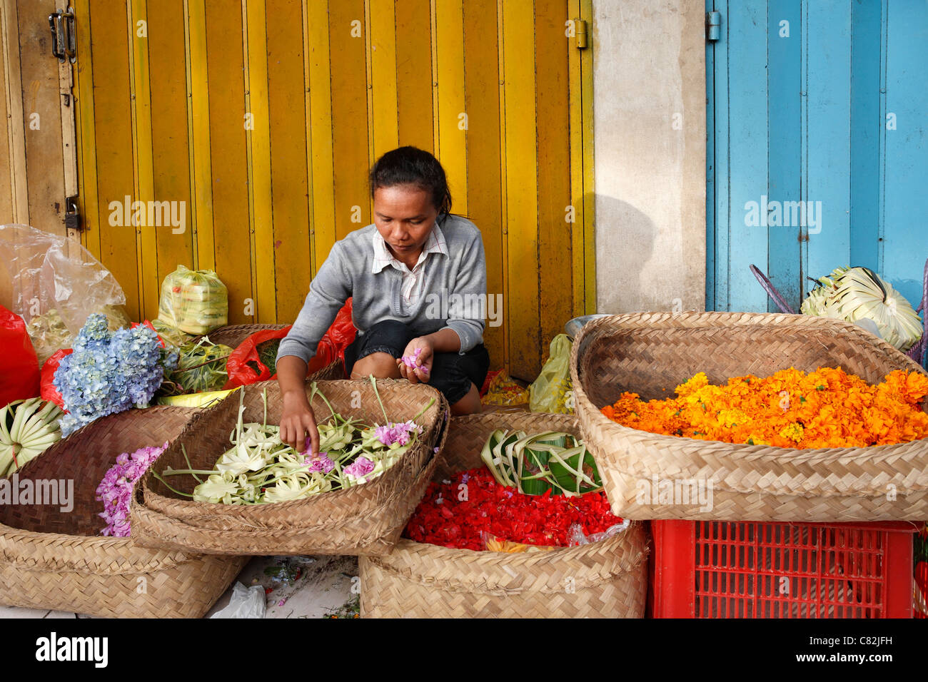 Femme balinaise en faisant des offrandes pour les vendre sur le marché traditionnel d'Ubud. Ubud, Bali, Indonésie Banque D'Images