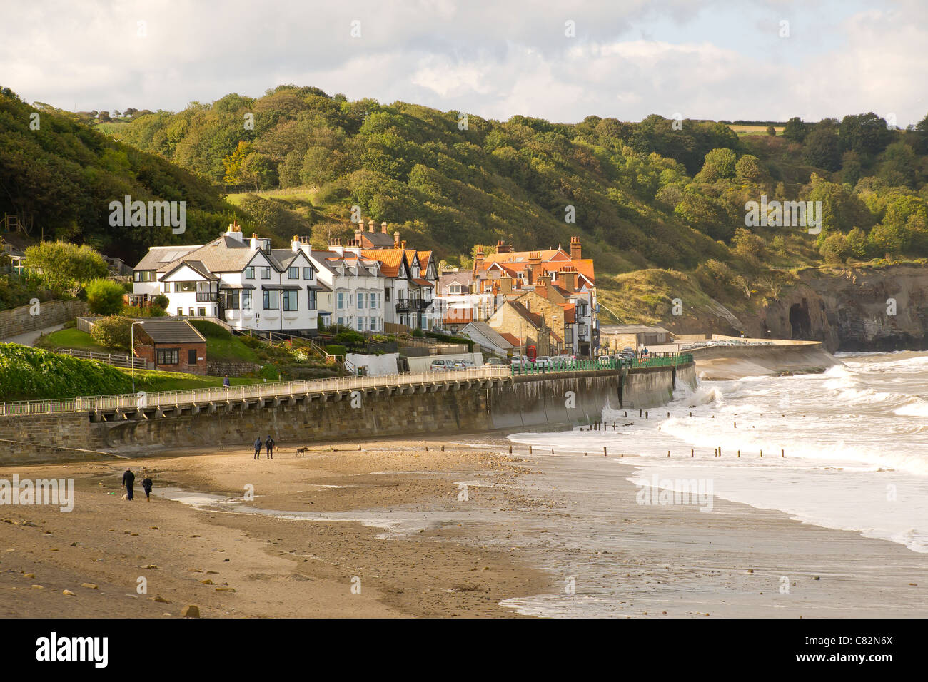 Les personnes qui usent de leurs chiens en automne soleil sur la plage de Sandsend près de Whitby, North Yorkshire Banque D'Images