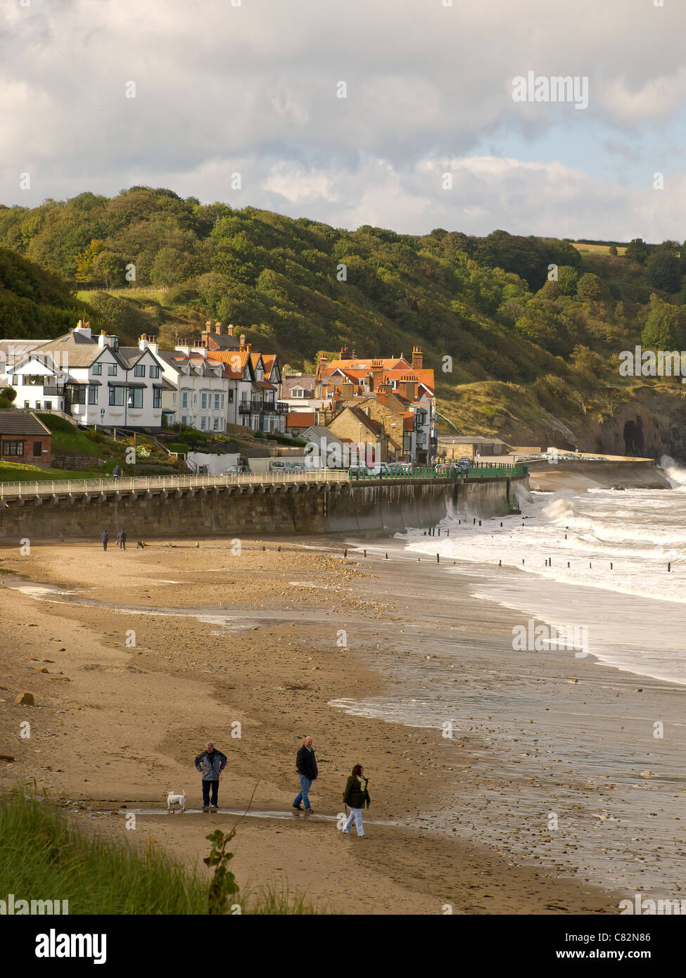 Les personnes qui usent de leurs chiens en automne soleil sur la plage de Sandsend près de Whitby, North Yorkshire Banque D'Images