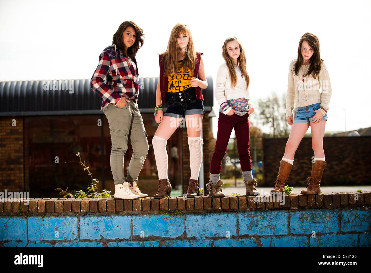 Un groupe d'adolescentes de 13 ans, moody avec attitude debout sur un mur UK Banque D'Images
