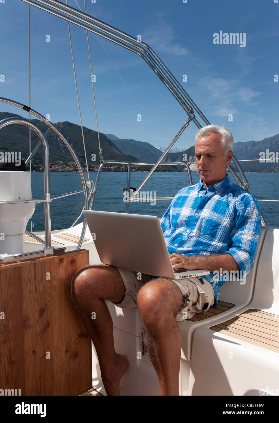 Homme plus âgé à l'aide de l'ordinateur portable sur voilier Banque D'Images