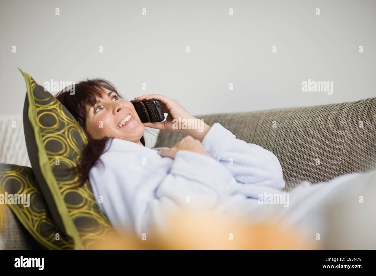 Woman in bathrobe talking on phone Banque D'Images