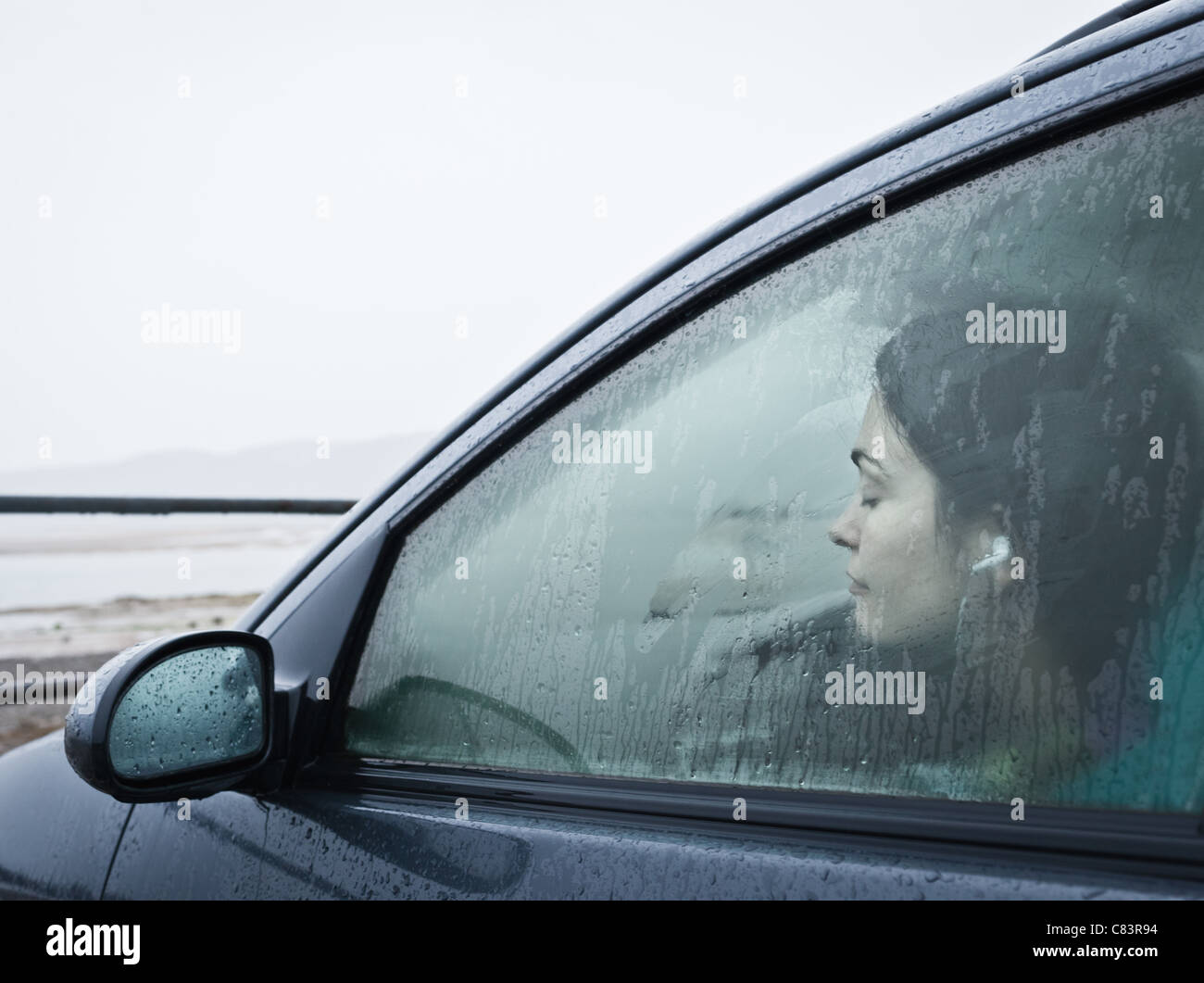 Teenage girl sitting in car par beach Banque D'Images