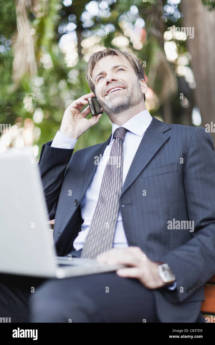Businessman working on laptop in park Banque D'Images