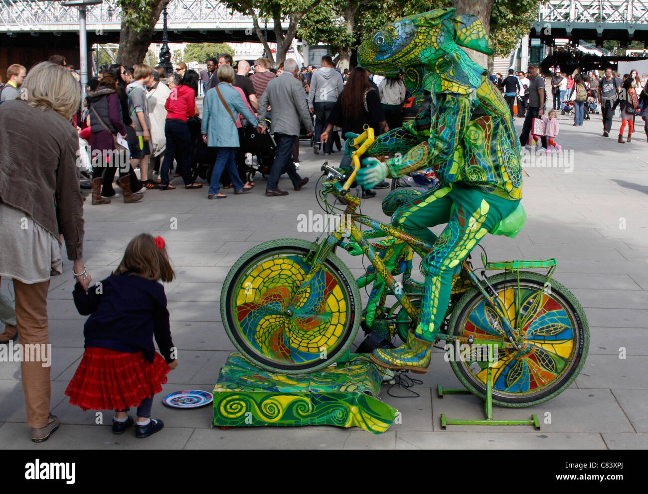 Artiste habillé comme un caméléon sur un vélo sur la rive sud de Londres Banque D'Images