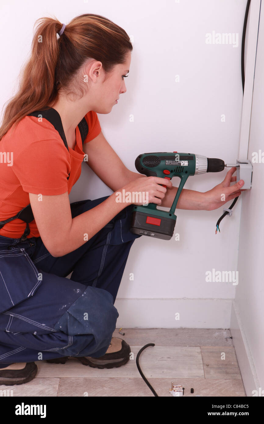 Un female electrician working on une prise électrique Banque D'Images